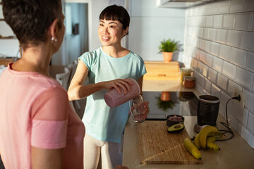 Lesbian couple making healthy organic smoothie together in modern kitchen