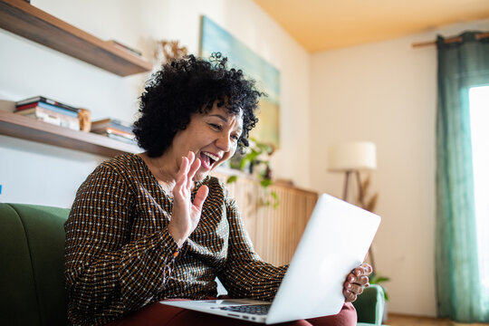 Smiling middle aged woman using laptop on home couch