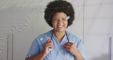 Smiling nurse holding stethoscope with world map and text image overlay