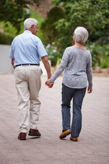 Senior couple, holding hands and walking with support in neighborhood for relationship, bonding or care. Back view, elderly man and woman with love for togetherness, dating or romance in retirement