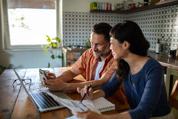 Couple managing bills with laptop on kitchen desk at home