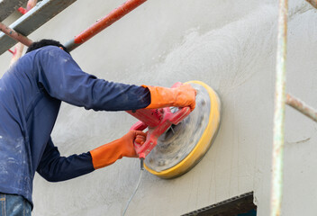 Worker use electric polishing machine mortar on wall.