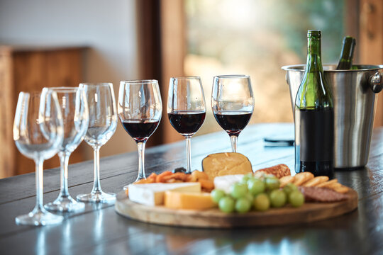 Wine tasting, glasses and cheese board at vineyard with drinks, bottle and fine dining. Party, celebration or pairing event with platter, food and fruit on table at winery with alcohol and liquid