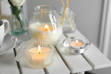 Beautiful burning candle on white wooden table, closeup © New Africa