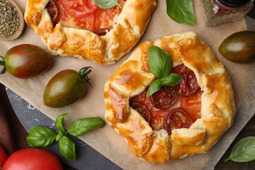 Tasty galettes with tomato and basil on wooden table, flat lay