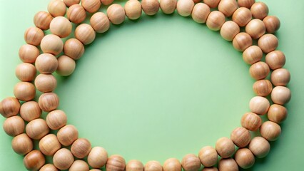 Obraz premium Wooden beads arranged in a circular pattern, creating a frame against a light green background.