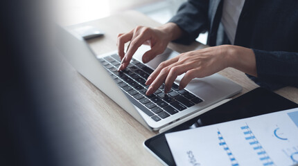 Businesswoman working on laptop computer with paperwork financial report, business document on office table. Business woman typing on laptop, analyzing and planning work project