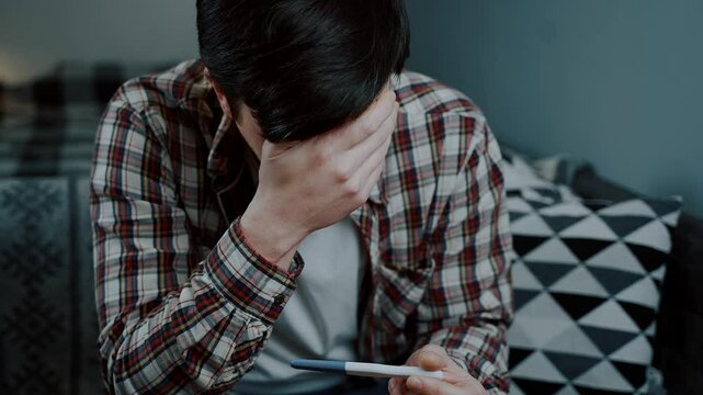 I am far to young to be father. Guy looks at result of pregnancy test and is very upset. I am not gonna be daddy anymore. Male frustrated with pregnancy test at home. Thinking of having an abortion