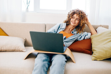 Smiling Woman Typing on Laptop, Enjoying Freelance Work in Cozy Living Room Environment