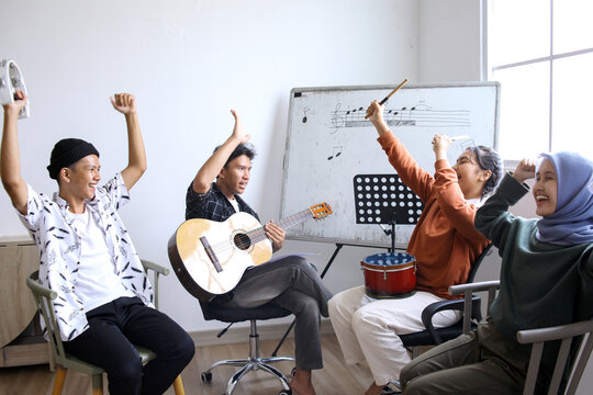 Happy Asian High School Students Learning Playing Musical Instrument And Singing In Class