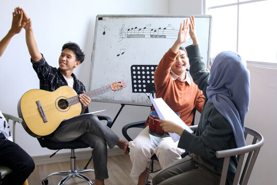 Happy Asian High School Students Learning Playing Musical Instrument And Singing In Class