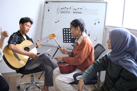 Happy Asian High School Students Learning Playing Musical Instrument And Singing In Class