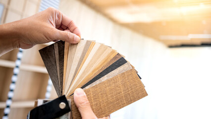 Designer hand picking sample of wood laminated material from natural collection. Customer choosing...