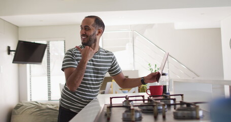 Smiling biracial man using tablet in kitchen
