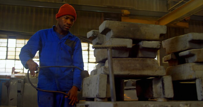 Worker heating metal mold with blow torch in foundry workshop