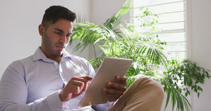 Front view of a biracial man working in a creative office and using a tablet computer