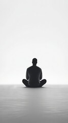 A man is sitting on the floor in a room. He is wearing a black shirt and black pants. The room is empty and the man is the only person in the room