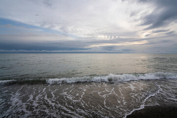 Fototapeta premium An incoming wave on the Black Sea coast against the sunset sky, Sochi, Krasnodar Territory, Russia