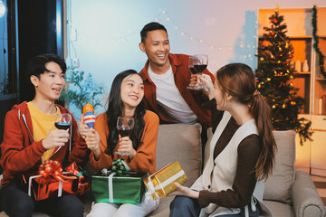 Group of young Asian man and women as friends having fun at a New Year's celebration, holding gift...