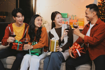 Group of young Asian man and women as friends having fun at a New Year's celebration, holding gift...