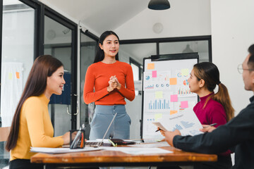 Fototapeta premium Business meeting with woman presenting data to colleagues in modern office. team is engaged, discussing strategies and analyzing charts on presentation board