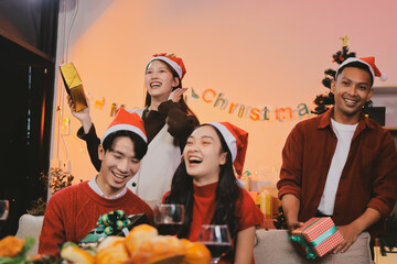 Group of young Asian man and women as friends having fun at a New Year's celebration, holding gift...