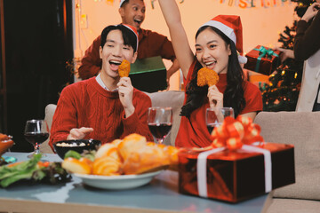 Group of young Asian man and women as friends having fun at a New Year's celebration, holding gift...