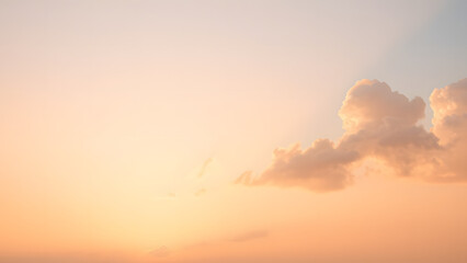 A sunrise background with golden clouds glowing softly against a light pink and blue sky
