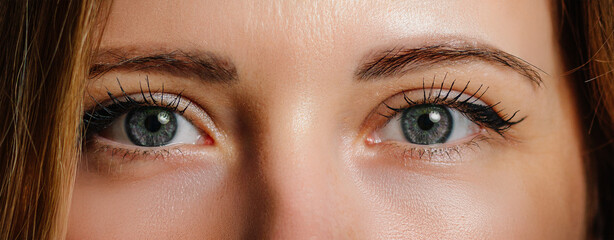 Close-up of a woman’s green eyes with detailed lashes and natural makeup, capturing clarity and...