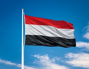 Yemen flag waving in the wind against a blue sky background