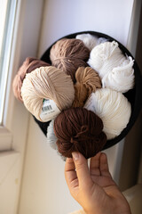 A close-up view of a collection of yarn balls in various shades of beige, white, and brown