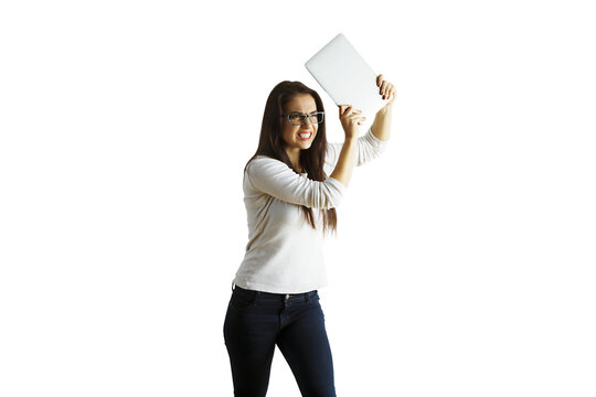 Woman in casual clothing holding a tablet above her head on a white background, isolated. Concept of frustration or stress with technology