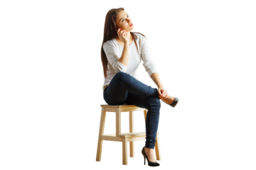 Woman seated on a wooden stool, dressed casually in a white top and jeans, looking thoughtful. Isolated on a clean white background, concept of contemplation