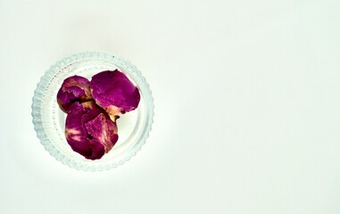 Dried peony flower tea buds in round glass bowl isolated on horizontal copy spaced white background from above angle view.
