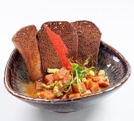 Salmon with Black Bread Puff Pastries on a Plate Against a White Background