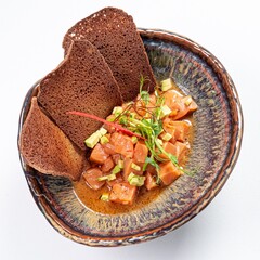 Salmon with Black Bread Puff Pastries on a Plate Against a White Background