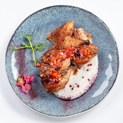 Fried Quail with Greens and White Sauce on a Plate Against a White Background