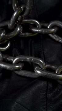Camera slowly moving over metal chain links on a dark leather background.
