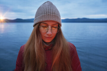 Portrait of pretty woman in glasses at the sunset on the lake
