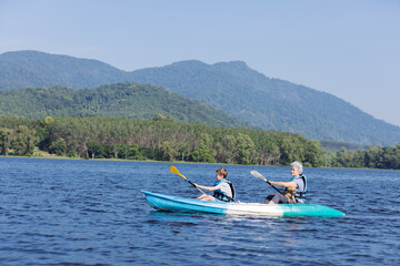 Fototapeta premium Grandmother and Grandson Kayaking with Their Dog on a Scenic Lake, Enjoying a Day Outdoors, Blue Waters, Sunny Day, Family Bonding, Adventure and Exploration in Nature, Peaceful and Relaxing Time