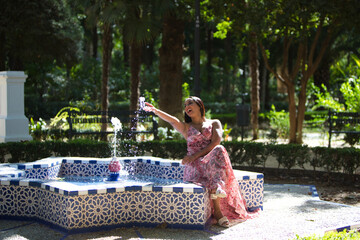beautiful young brunette woman in a long flower patterned dress is sitting in a star-shaped...