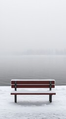 Obraz premium A solitary red bench covered in snow along a serene, foggy lakeside landscape.