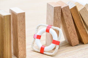 Risk management, crisis prevention, contingency planning, and risk mitigation : A red lifebuoy stands in front of a row of wooden blocks, symbolizing the importance of proactive risk management.