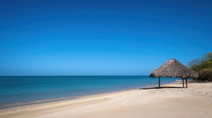 A beach with a small hut and a clear blue sky