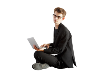A young man in asuit and glasses sitting cross-legged while using a laptop on a white background. Concept of professionals and remote work