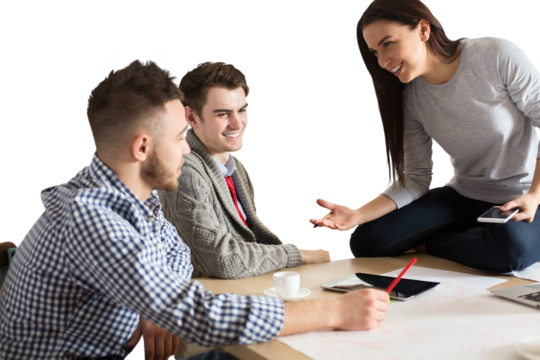Group of three young professionals discussing ideas with charts, sketches, and devices on a table, isolated on white background, teamwork concept - Powered by Adobe