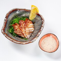 Eel with Chuka Salad, Sauce, and Sesame on a Plate Against a White Background