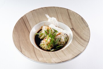 Large Gyoza Dumplings Made of Rice Dough with Sauce in a Bowl Against a White Background