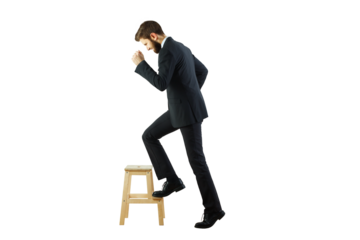 Side view of a businessman in asuit stepping on a wooden stool, isolated on white background. Concept of ambition and career growth
