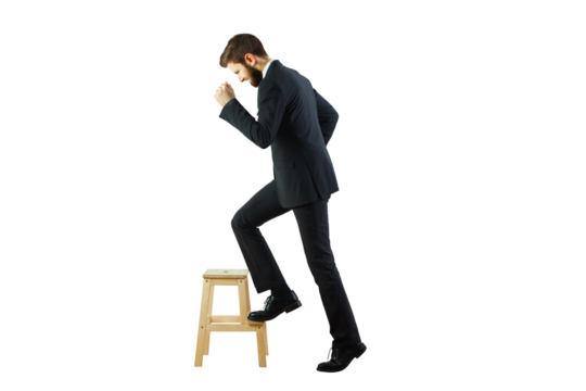 Side view of a businessman in asuit stepping on a wooden stool, isolated on white background. Concept of ambition and career growth